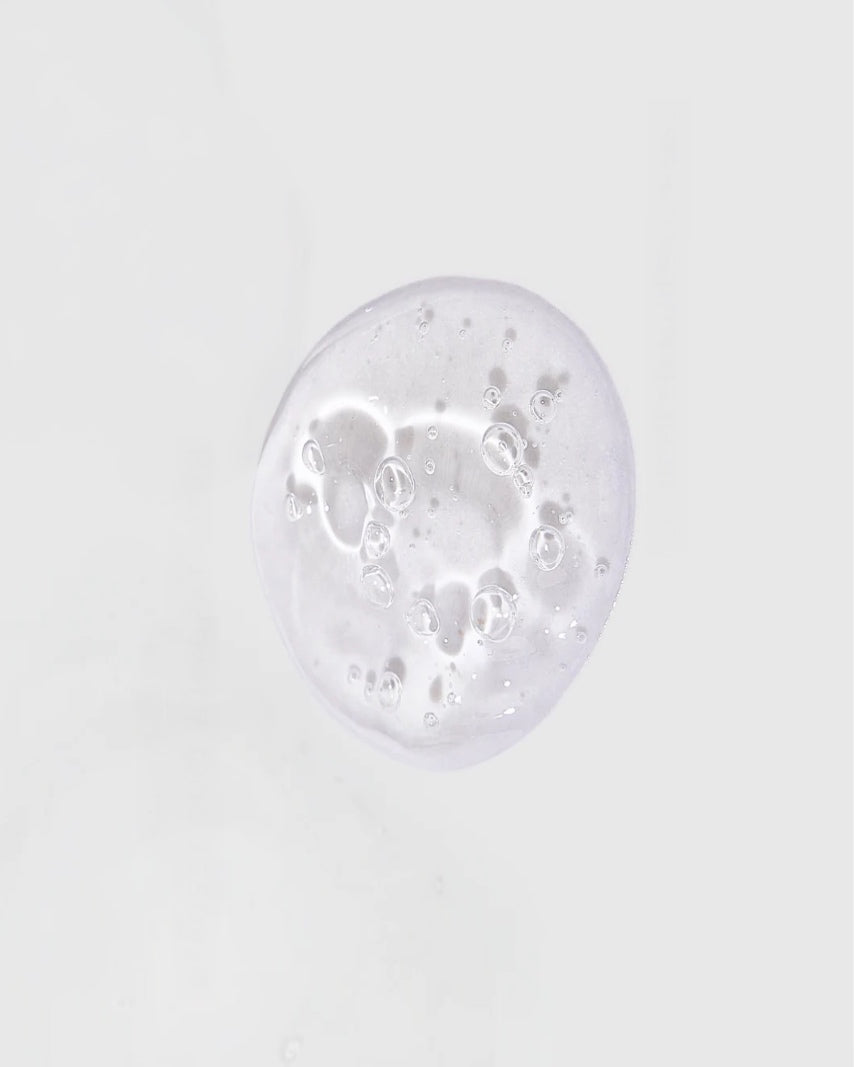 Goutte de colle corporelle KLEVA transparente avec bulles, illustrant sa texture légère, invisible et facile à appliquer sur la peau.